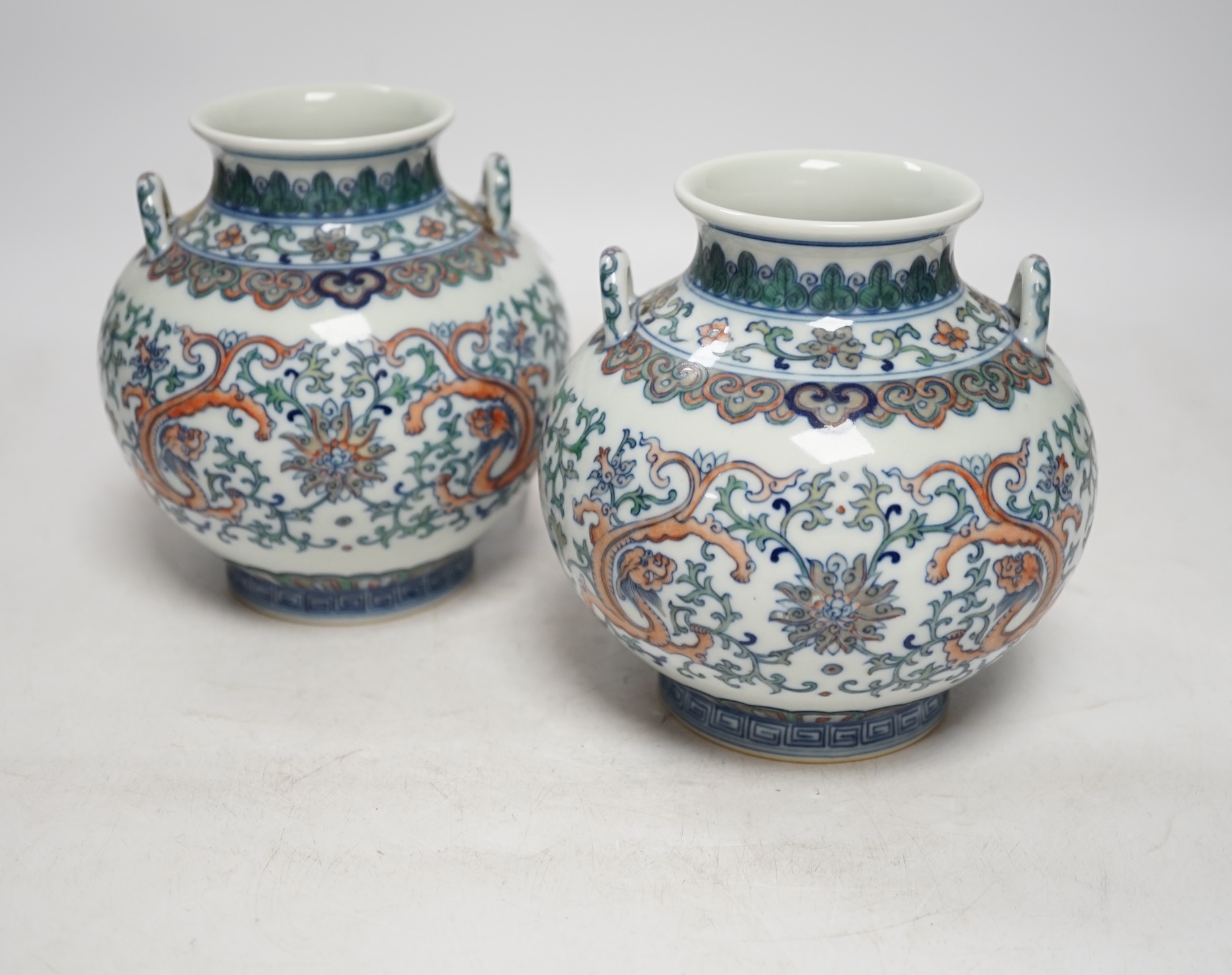 A pair of Chinese porcelain doucai twin handled ‘dragon’ jars, 14cm high. Condition - good